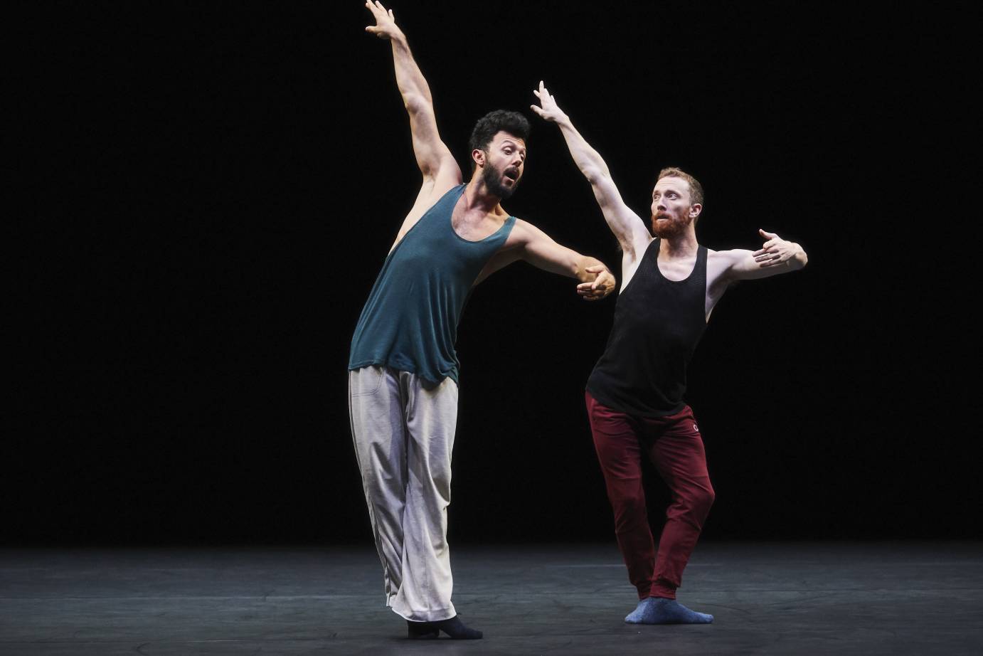 Two male dancers lift their arms and twist their bodies